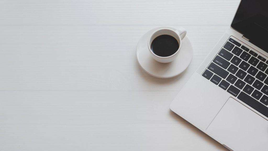 laptop and coffee on desk in office
