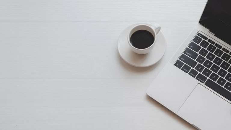 laptop and coffee on desk in office