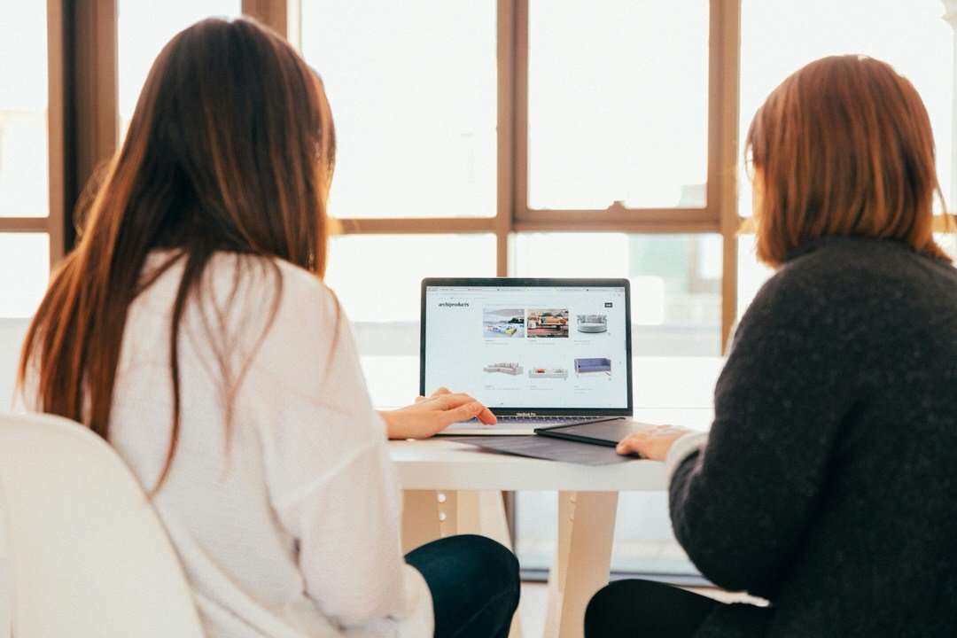Two women working together at a table with a laptop