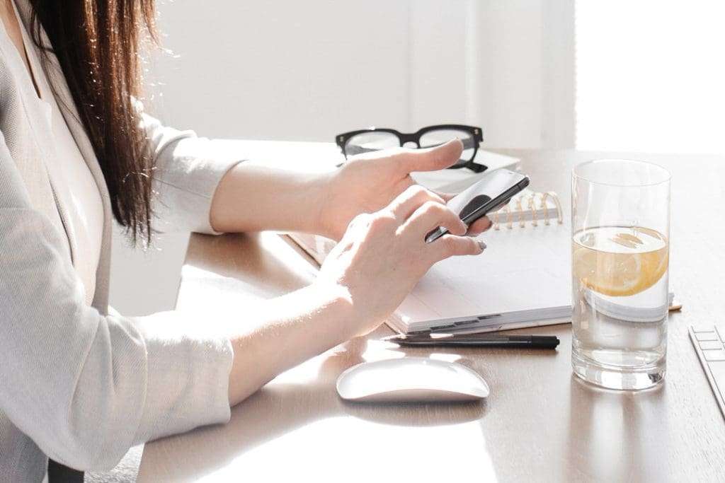 Female at desk with glass of water and mobile phone