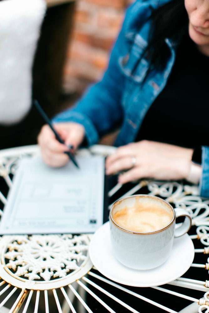 Writing notes in a cafe, with a latte on the table.